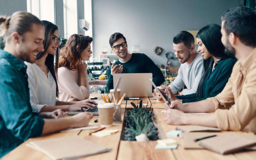 Marketing team. Group of young modern people in smart casual wear discussing something while working in the creative office