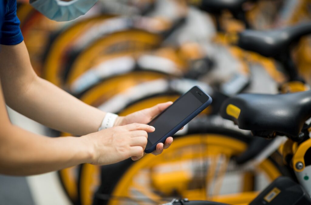 Hands using smartphone scanning the QR code of shared bike in city